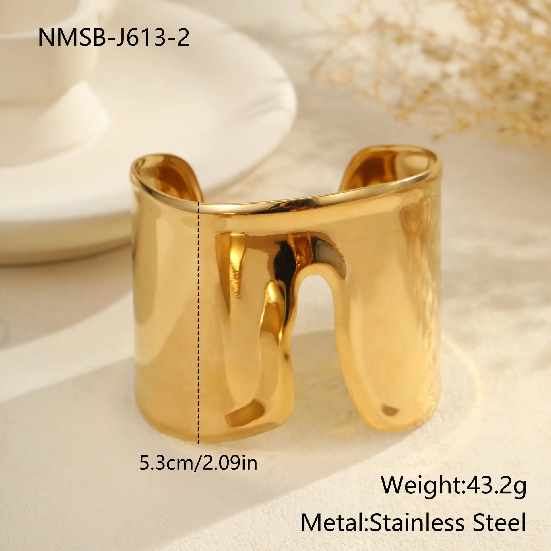Gold plated wide stainless steel bracelet with a geometric wave shape and a niche opening.