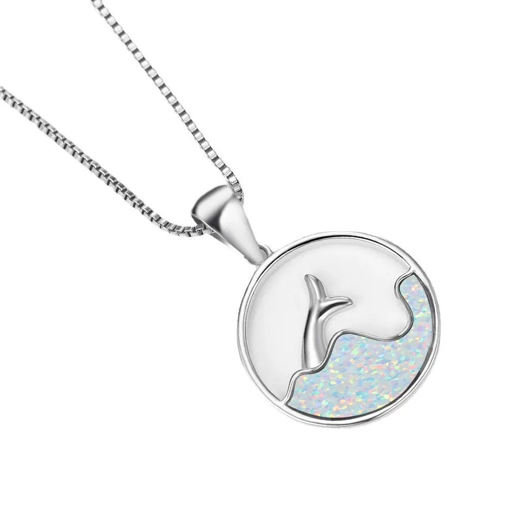 Close-up of a white gold plated sea fishtail pendant necklace with a round blue opal stone.