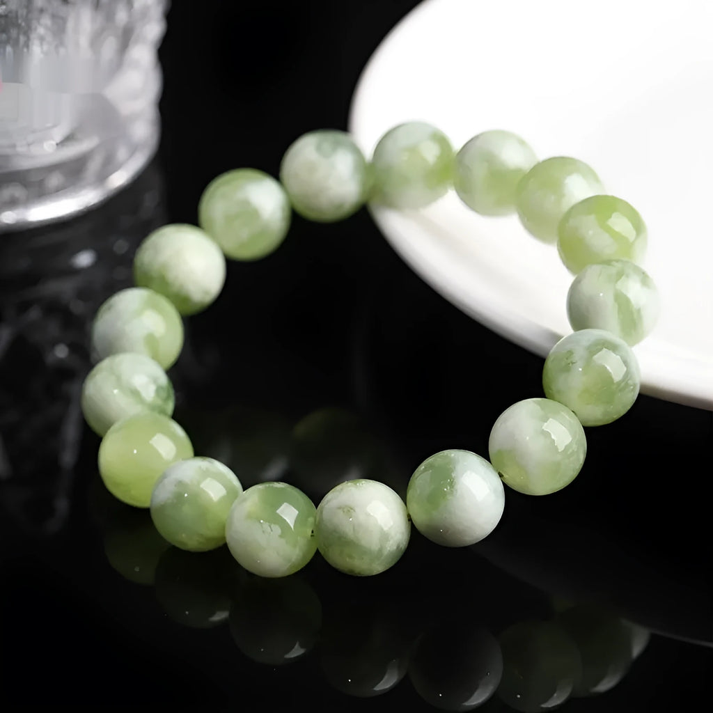 Green milk-in-water Xiuyan jade polished bracelet with geometric beads on a neutral background