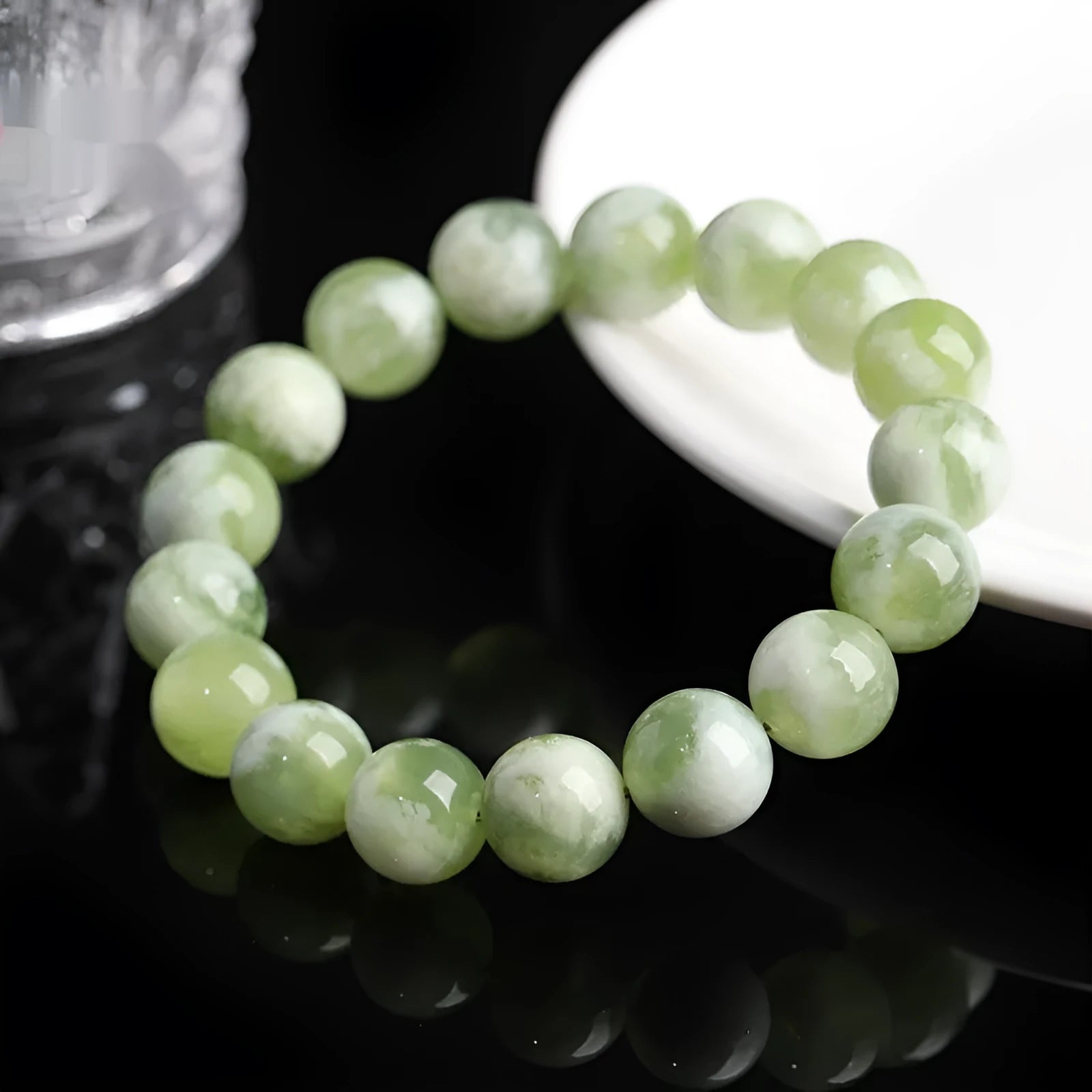 Green milk-in-water Xiuyan jade polished bracelet with geometric beads on a neutral background