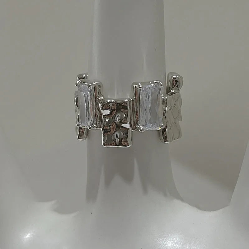 Silver geometric open ring with cross design and zircon decoration on white background