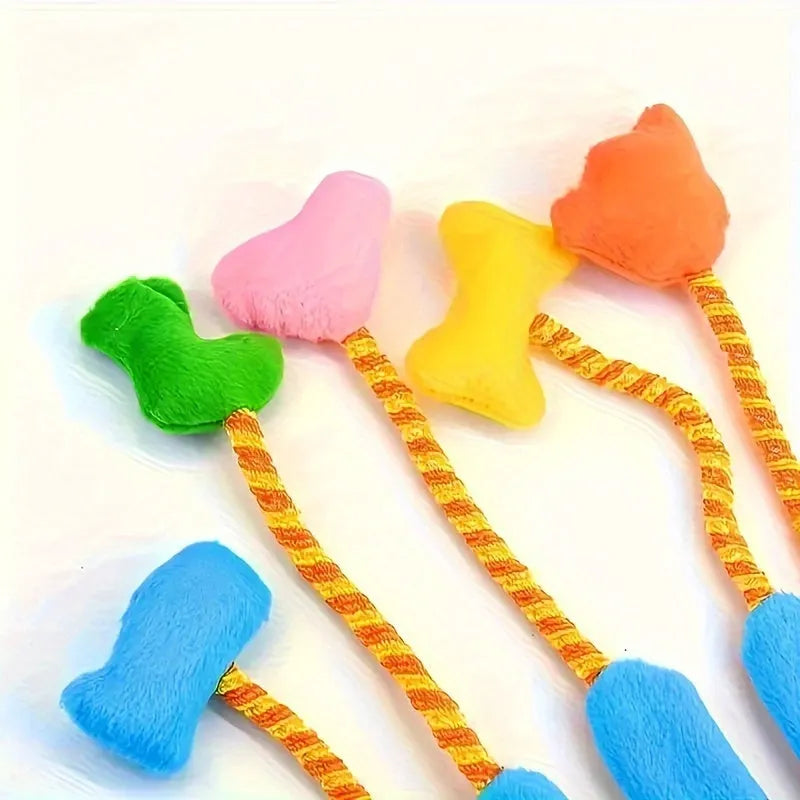 Yellow and blue plush cat toy with a bell and magic glove handle on a plain background.