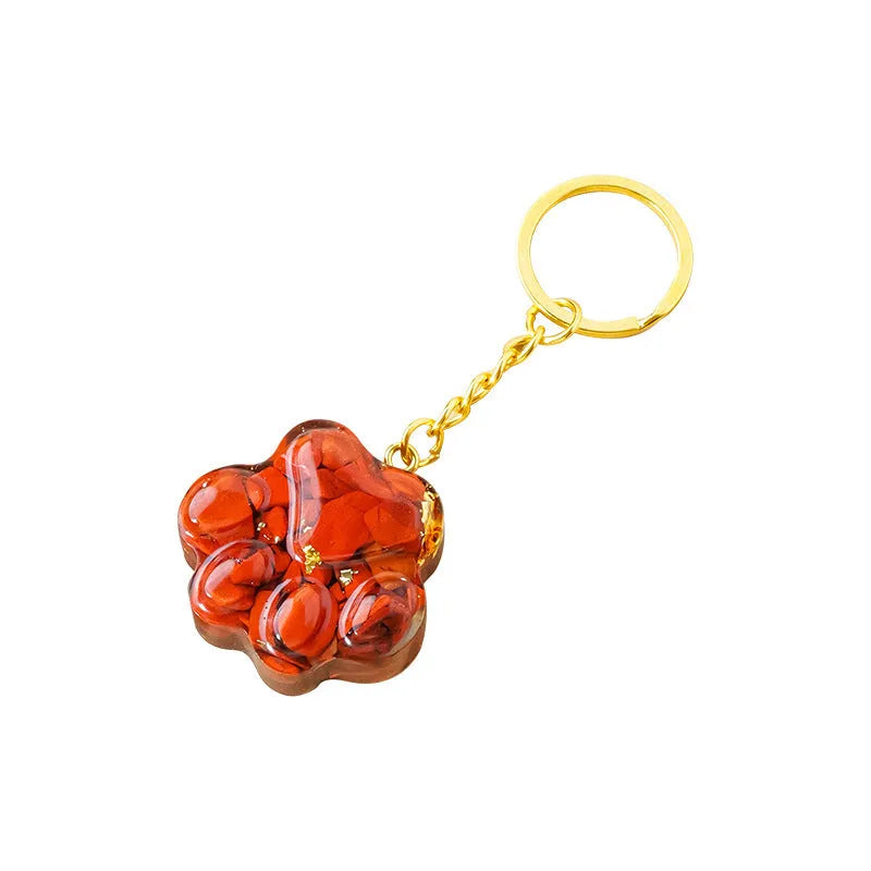 Small natural crystal cat's paw charm on a keyring, showing colour options including pink, red, blue, and purple gemstones.