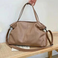 Large soft surface black messenger bag with soft handle and long shoulder strap on a table
