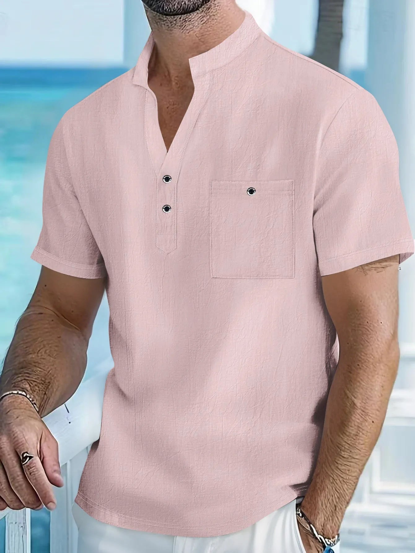 Man wearing a light-coloured, loose fit linen t-shirt with a stand collar and short sleeves.
