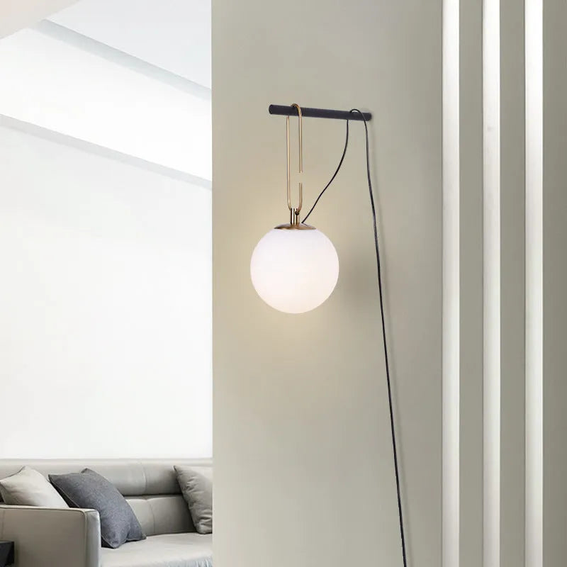 Contemporary clear glass wall light fixture with modern design on a white wall.
