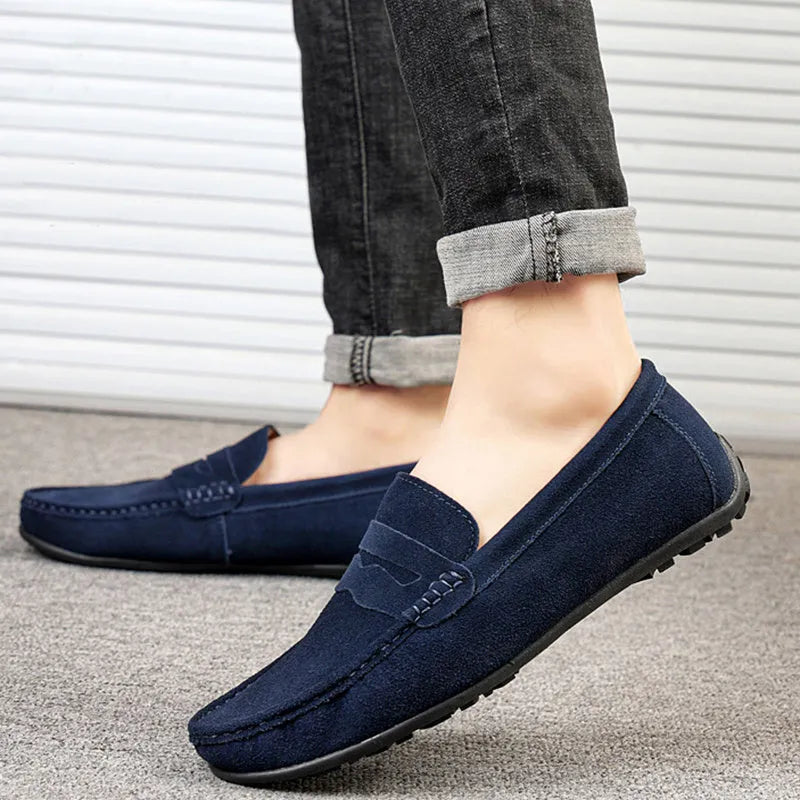 Men's solid colour suede loafers with round toe and rubber sole on a neutral background.