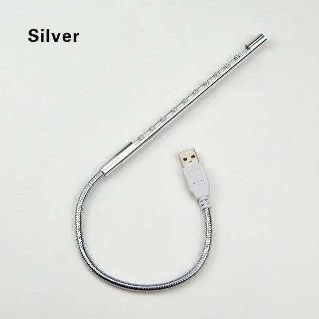 Black aluminium alloy spiral USB LED night light on a desk next to a laptop
