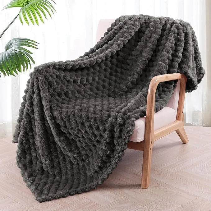 Soft camel-coloured plaid fleece blanket for children folded on a bed.