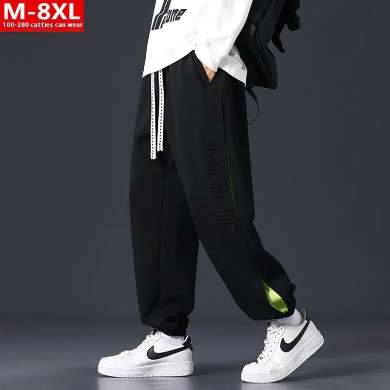 Men's loose black cotton trousers with white collage stitching print and banded ankle cuffs laid flat.