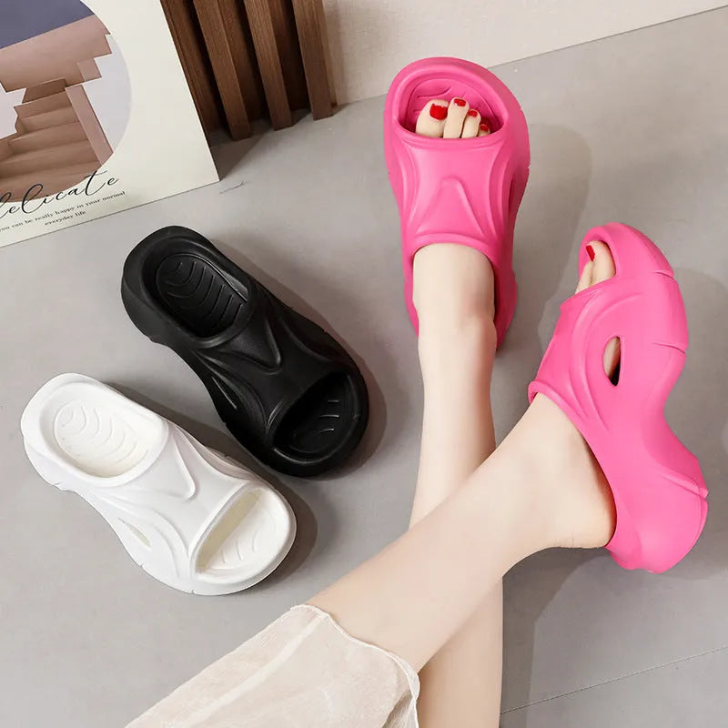 Women's thick-soled EVA slippers in rose red colour on a sandy beach.