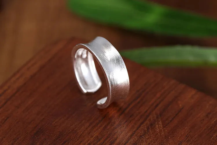 Frosted silver geometric open ring with adjustable sizing on a neutral background