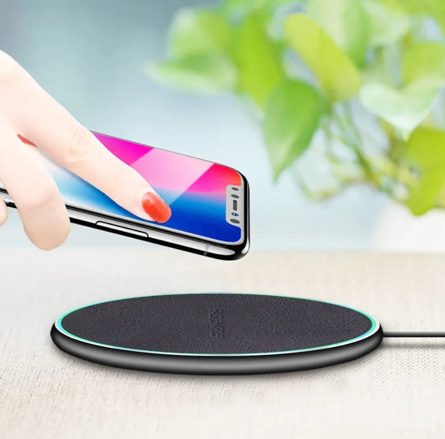 Black Qi wireless fast charging pad for iPhone 11 on a wooden surface.