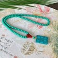 Turquoise lucky pendant necklace with hand-woven mesh flower design on a ball bead chain.