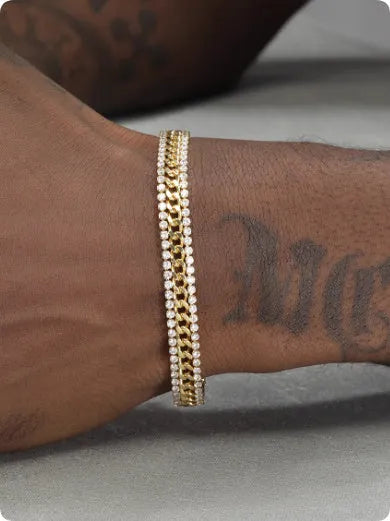Gold coloured hip hop style tennis bracelet with stone inlay on a wrist.