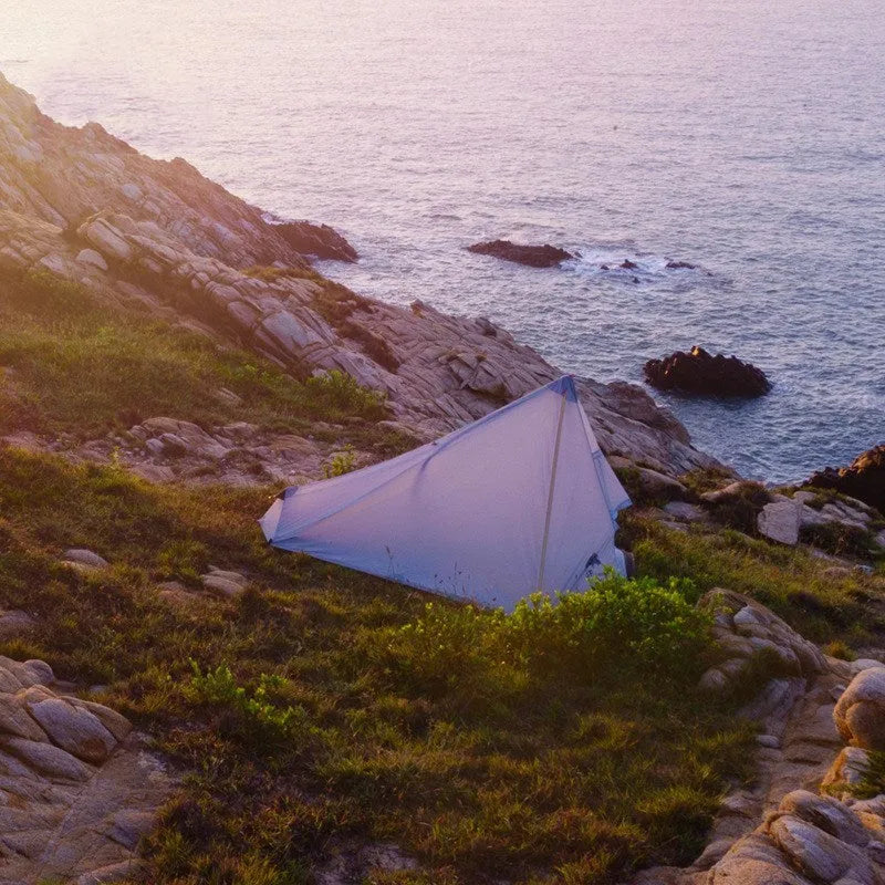 Green silicon coated outdoor camping pyramid tent pitched on grass with aluminium pole and reflective wind ropes