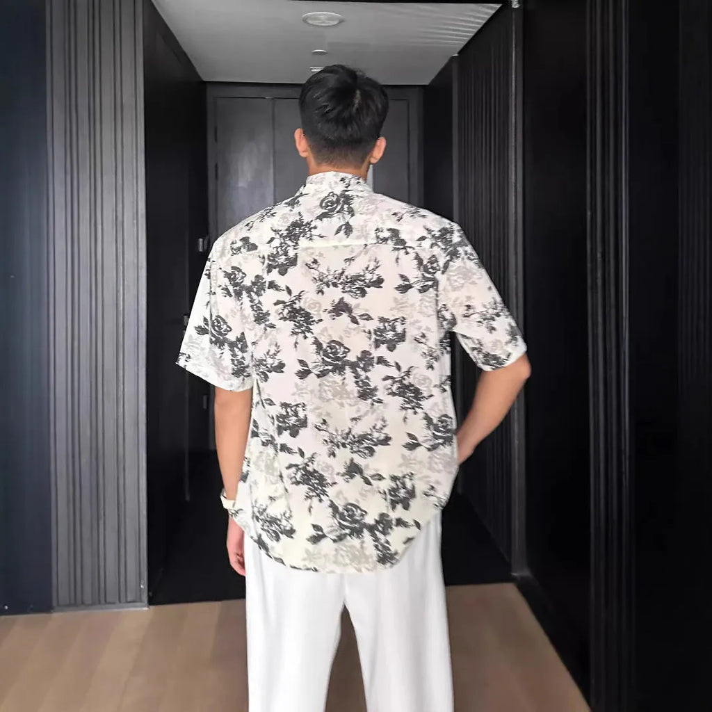 Man wearing a loose black floral print casual short sleeve shirt.