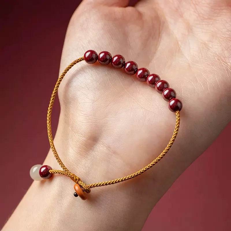Hand-woven geometric bracelet made from raw Cinnabar and Hetian Jade ore on a wrist.