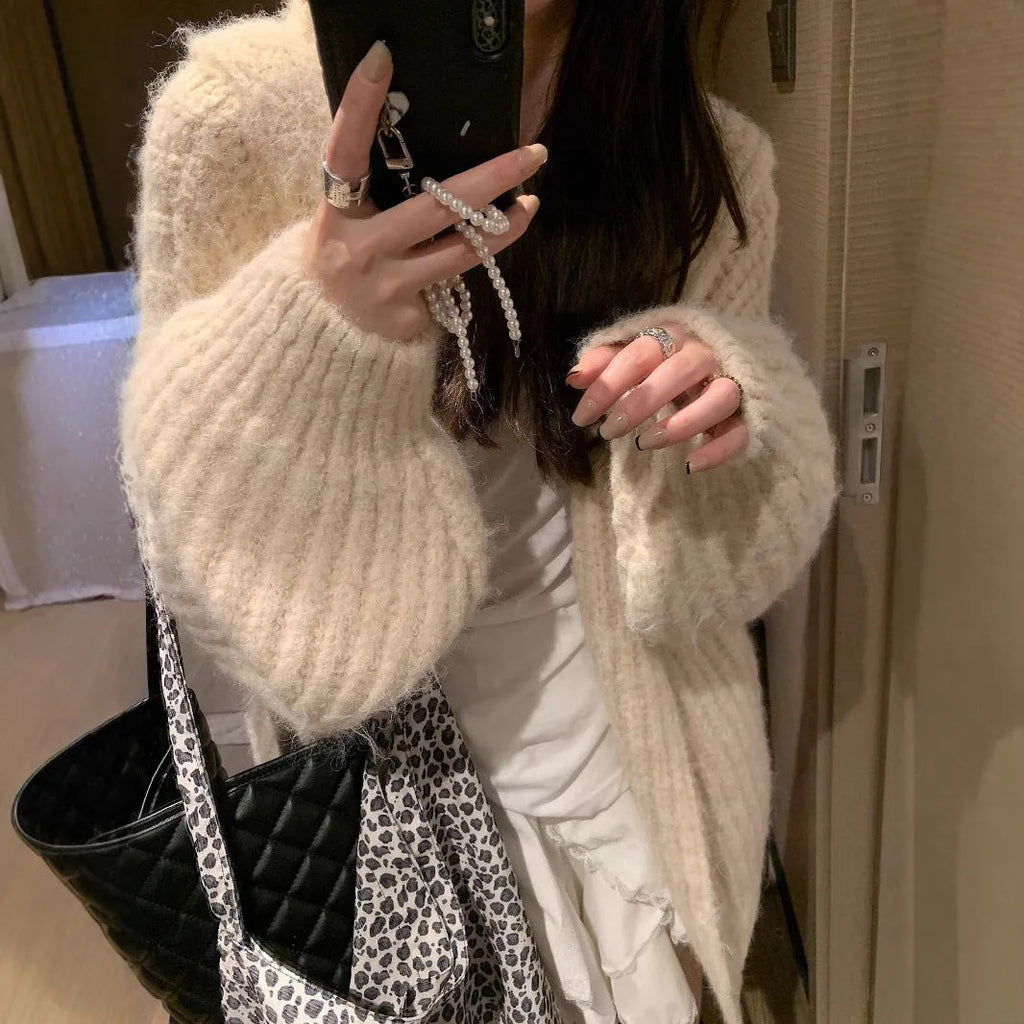 Woman wearing a loose-fit, chunky knit hooded cardigan in a macaron colour.