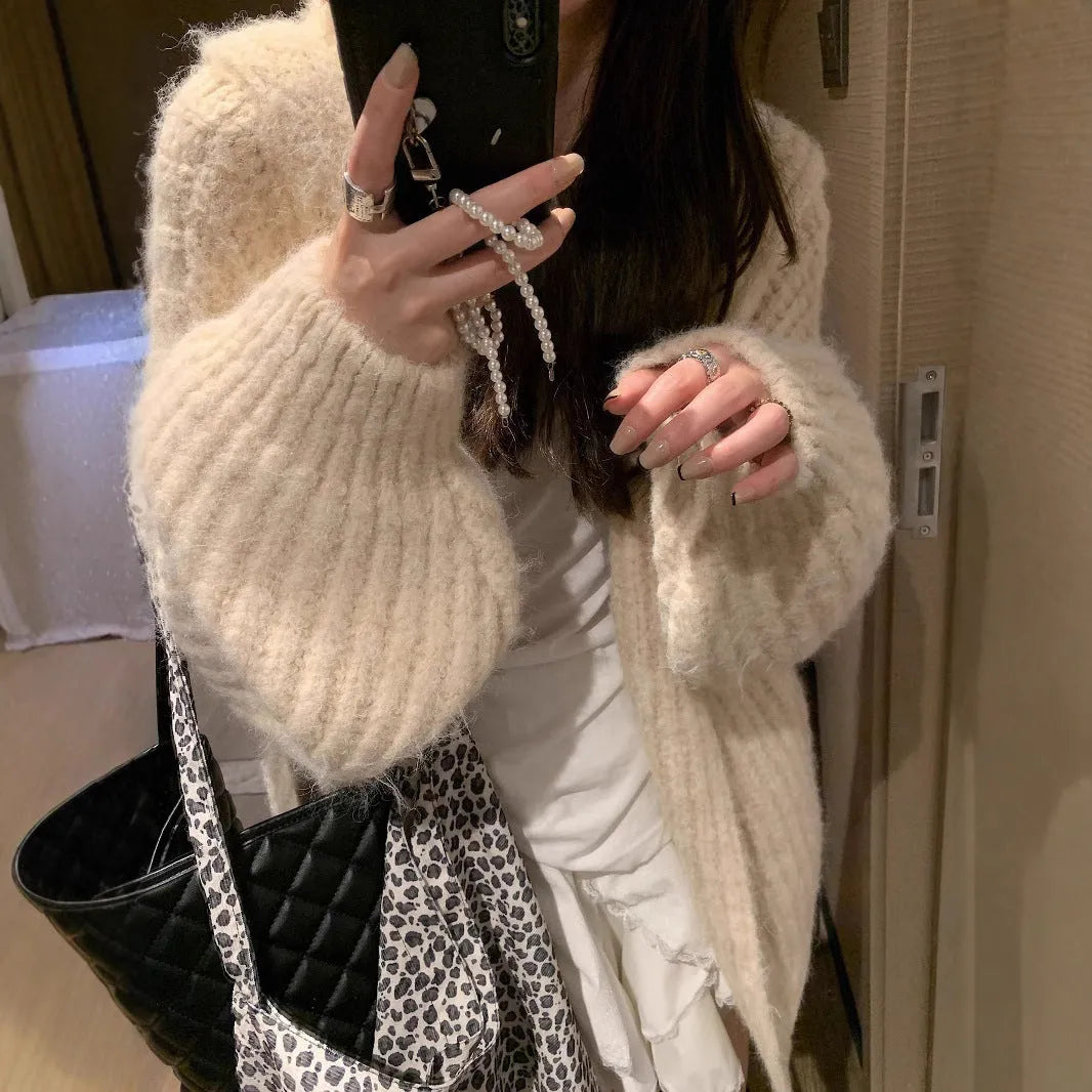 Woman wearing a loose-fit, chunky knit hooded cardigan in a macaron colour.