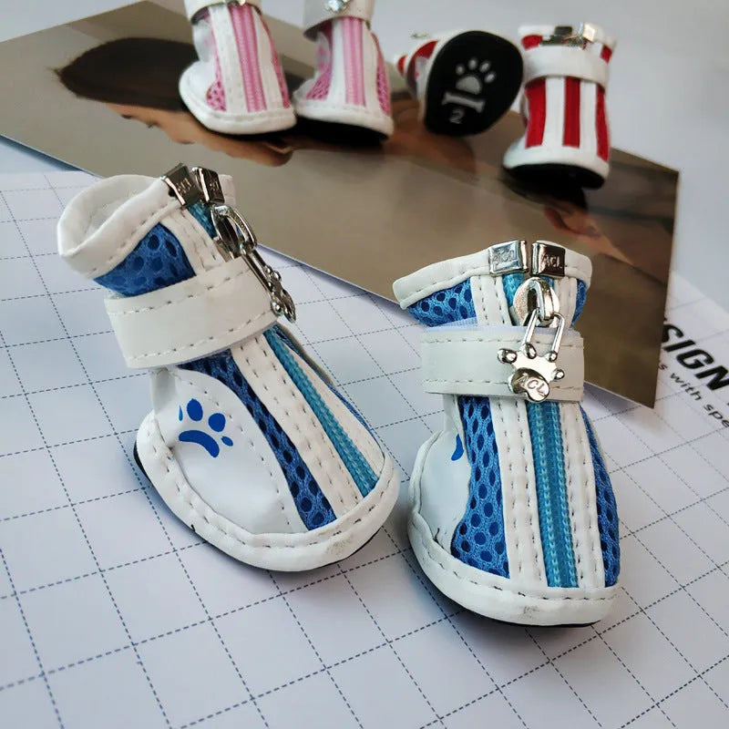 Four blue cloth dog shoes with zipper closures, shown on a small dog's paws.