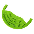 Black silicone food oil drainer snapped onto a pot rim, with liquid being poured off