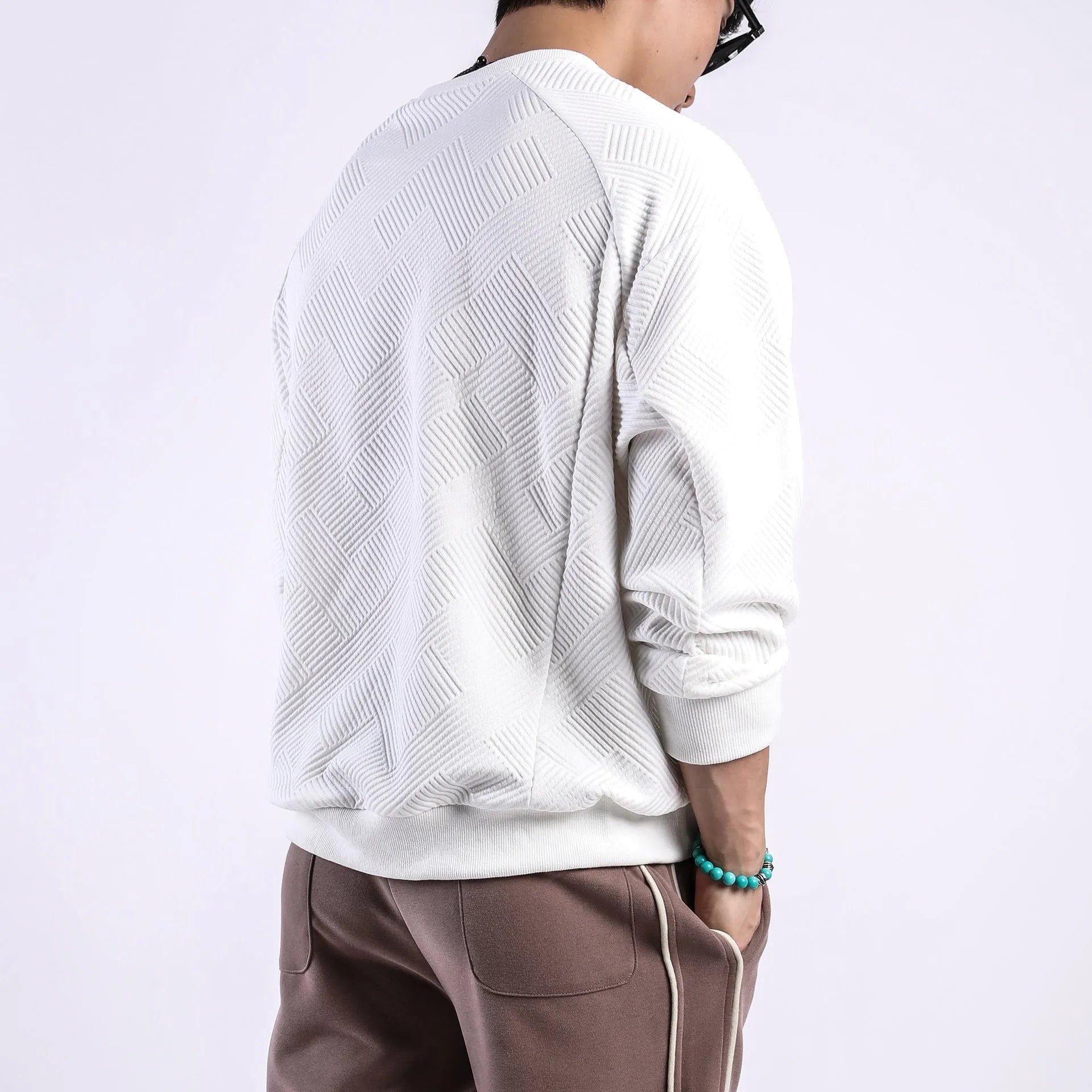 Man wearing a loose-fit army green twill jacquard long-sleeved pullover sweater.