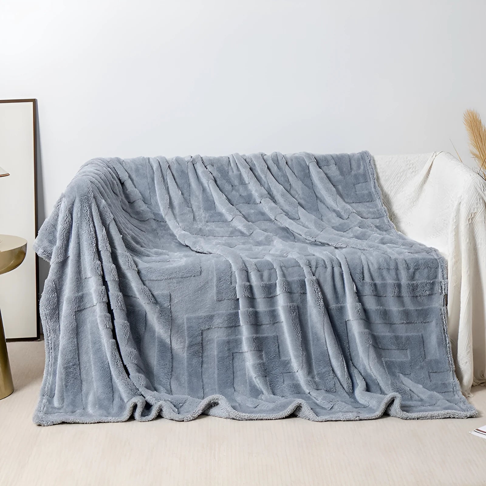 Thick square coral fleece blanket in a solid colour, draped over a sofa.