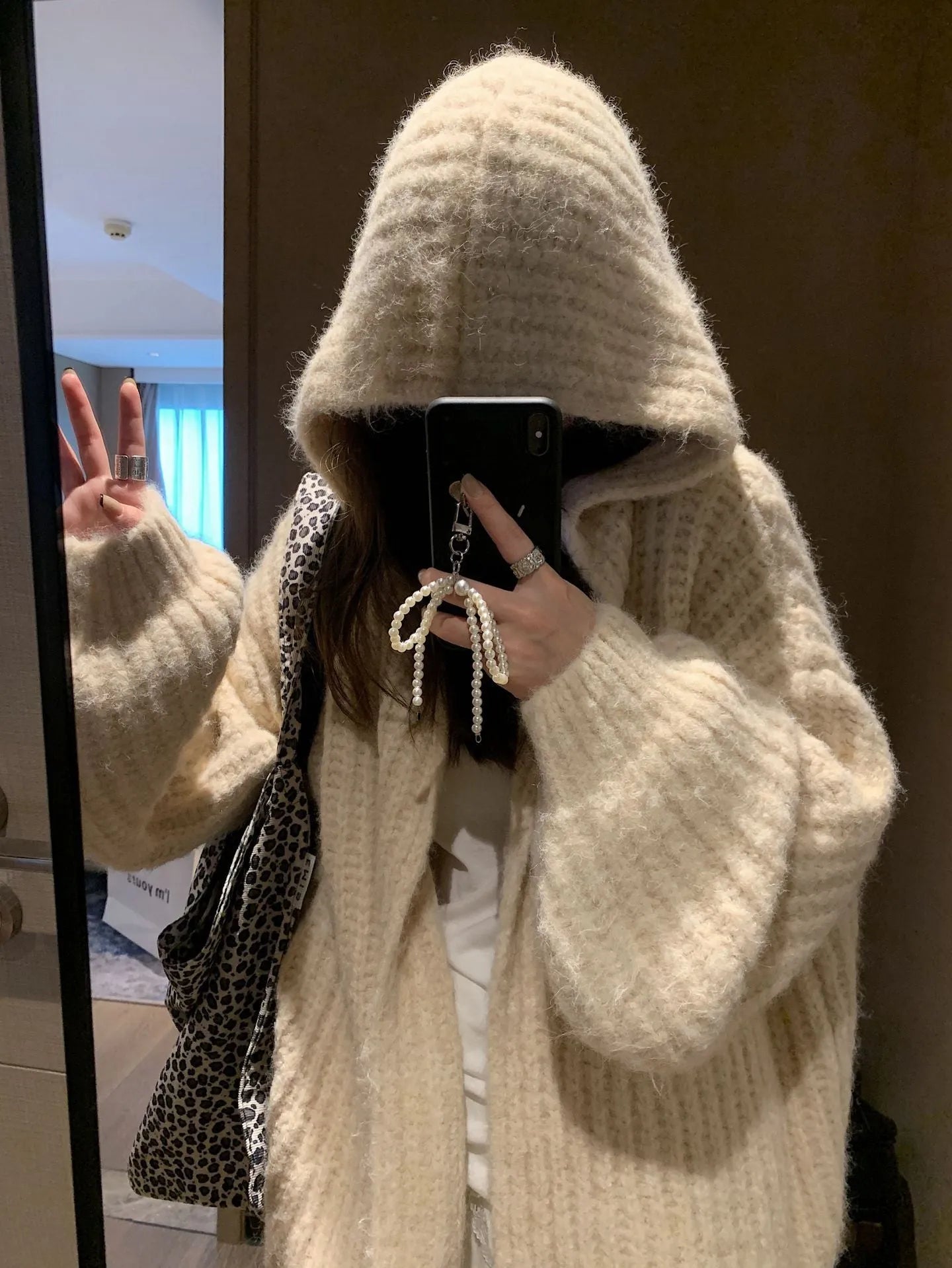 Woman wearing a loose-fit, chunky knit hooded cardigan in a macaron colour.