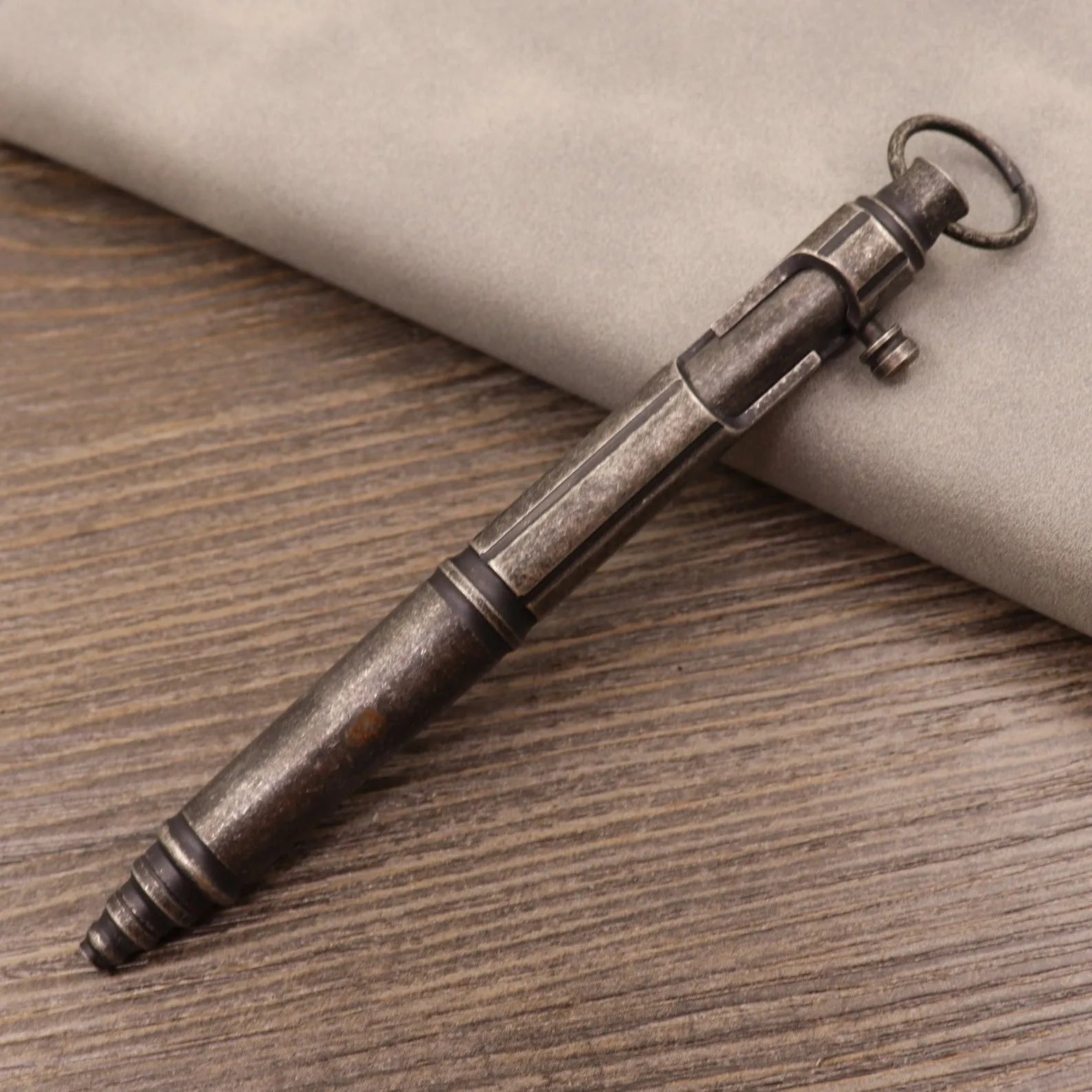 Close-up of a solid brass bolt action tactical pen with a press mechanism on a dark surface.