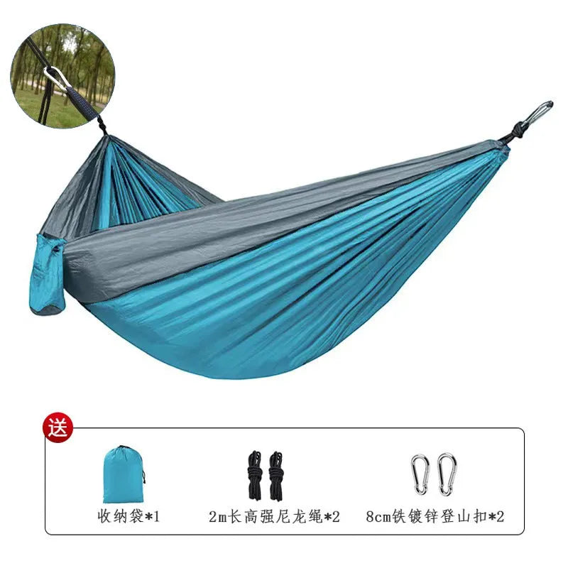 Blue ripstop nylon outdoor hammock with suspension ropes hung between trees
