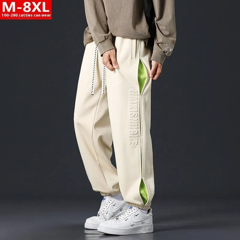 Men's loose black cotton trousers with white collage stitching print and banded ankle cuffs laid flat.