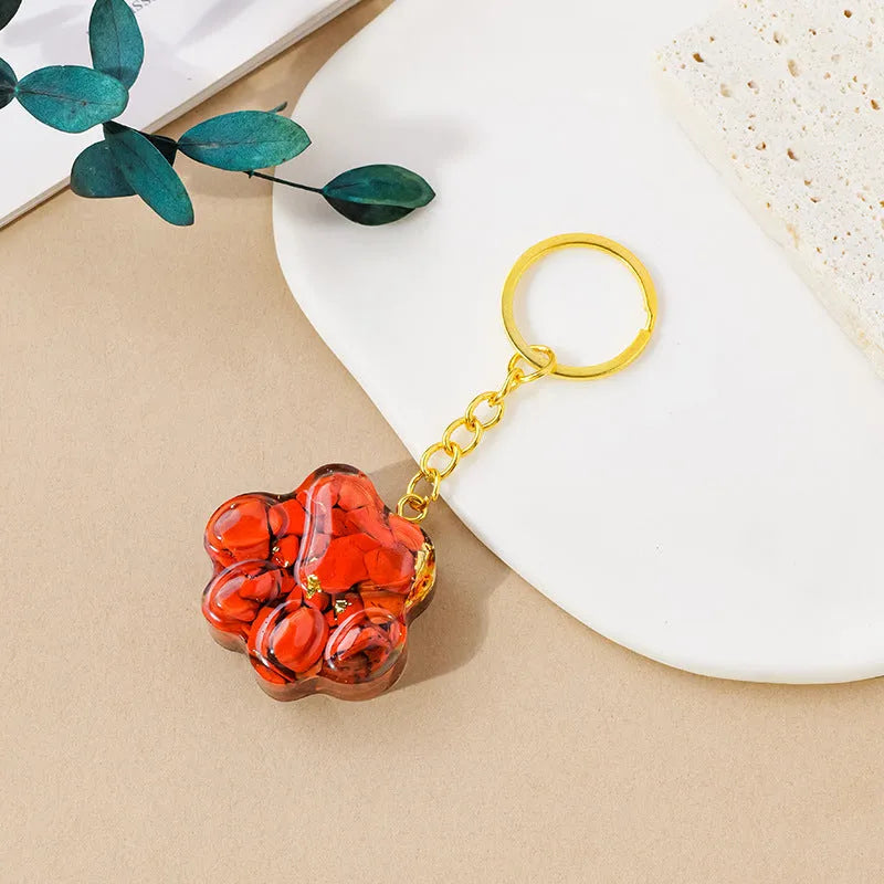 Small natural crystal cat's paw charm on a keyring, showing colour options including pink, red, blue, and purple gemstones.