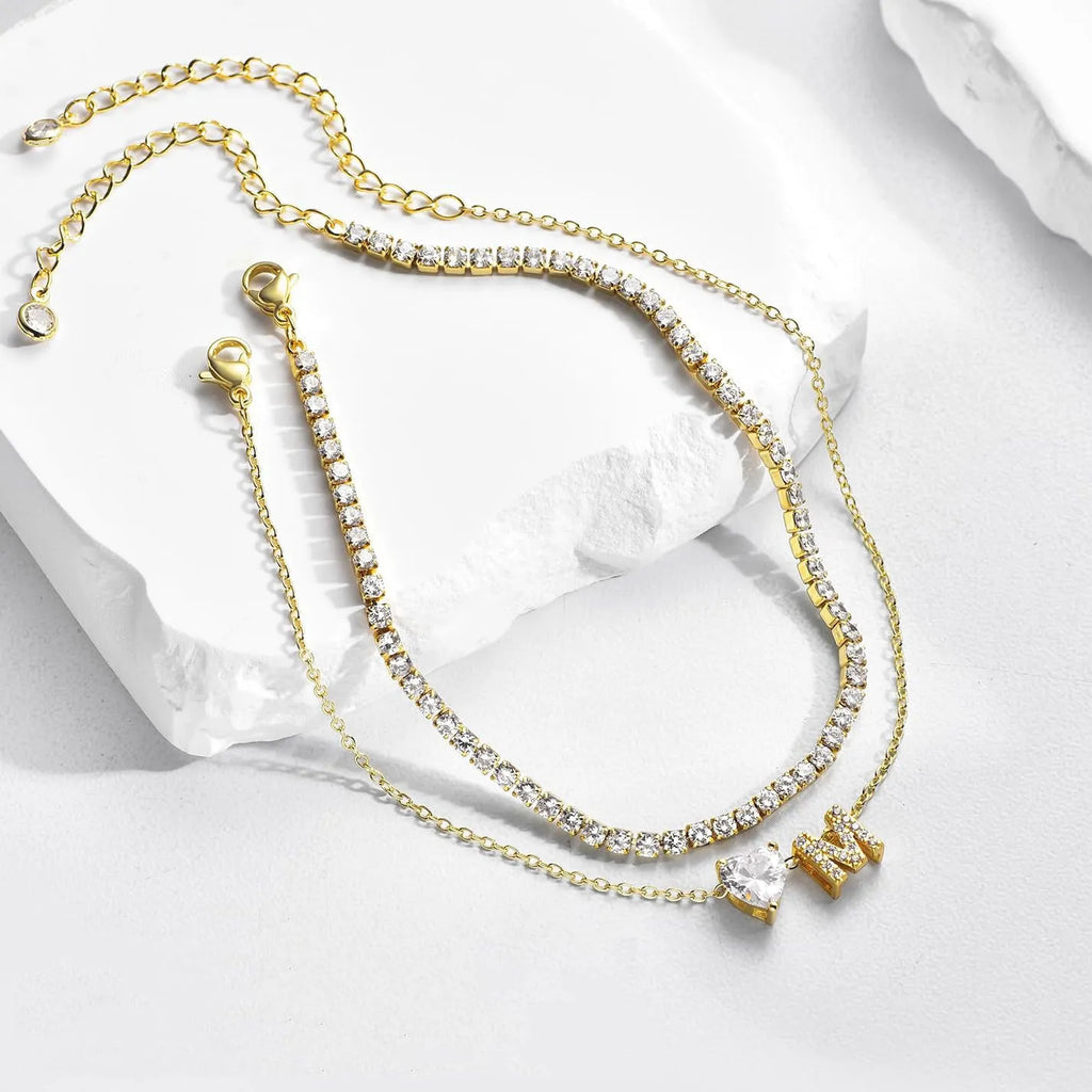 Layered copper anklet with zircon inlaid letter charm, bead zircon style, on a light background.