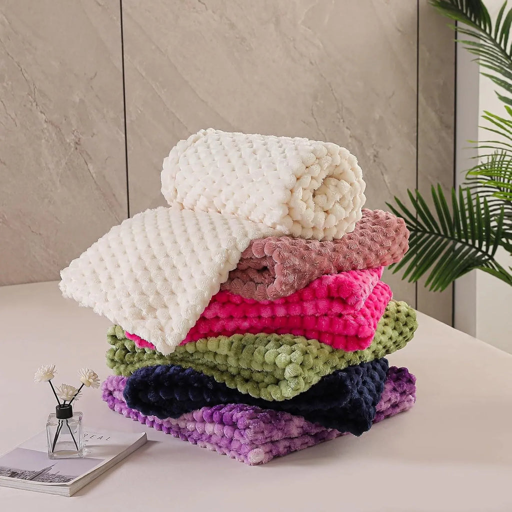 Soft camel-coloured plaid fleece blanket for children folded on a bed.