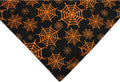 Reversible black and orange Halloween dog bandana with pumpkin and spider web patterns laid flat