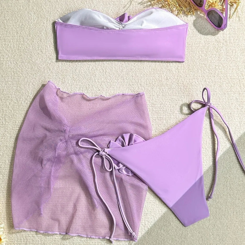 Women's pink swimsuit set with a large 3D flower tie, matching pants, and a separate skirt.