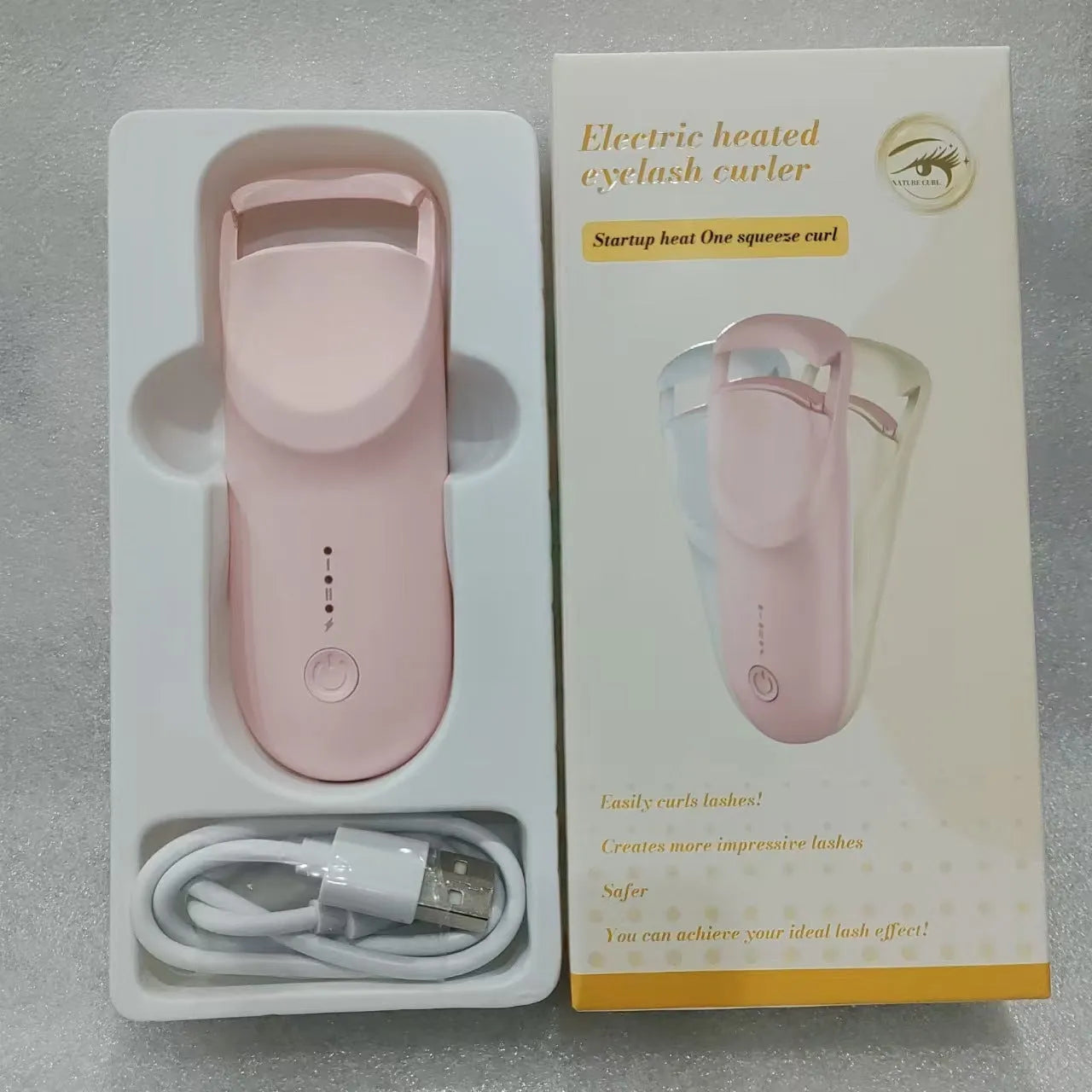 Electric heating eyelash curler in plastic housing with USB cable on a vanity