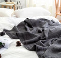 Fringed acrylic knit ball blanket 130x170cm in beige on a sofa