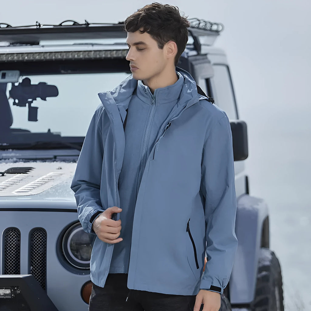 Man wearing a black waterproof mountaineering suit jacket and trousers set for outdoor hiking.