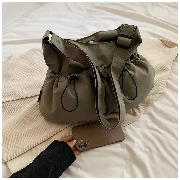 Green pleated crossbody student bag showing foldable polyester construction and internal mobile phone pocket