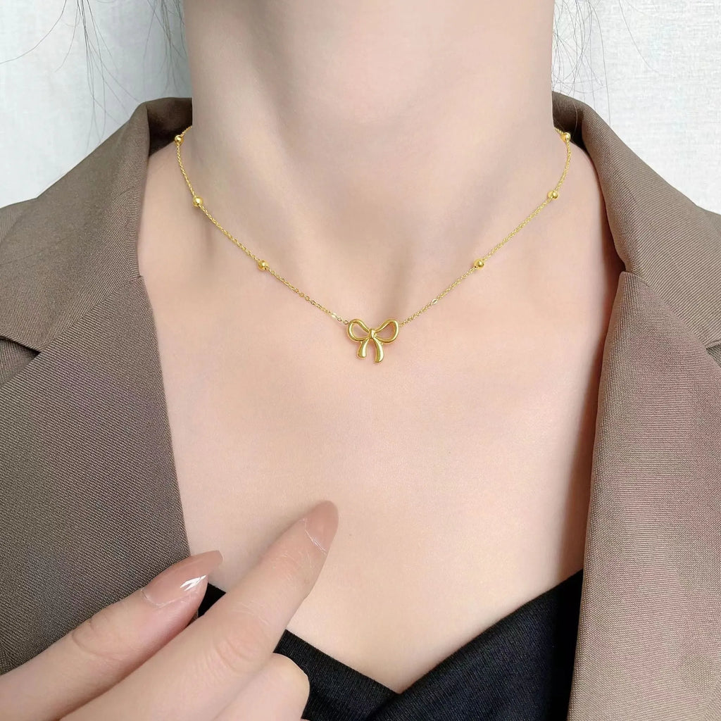 Gold bow necklace with titanium steel cross chain on white background