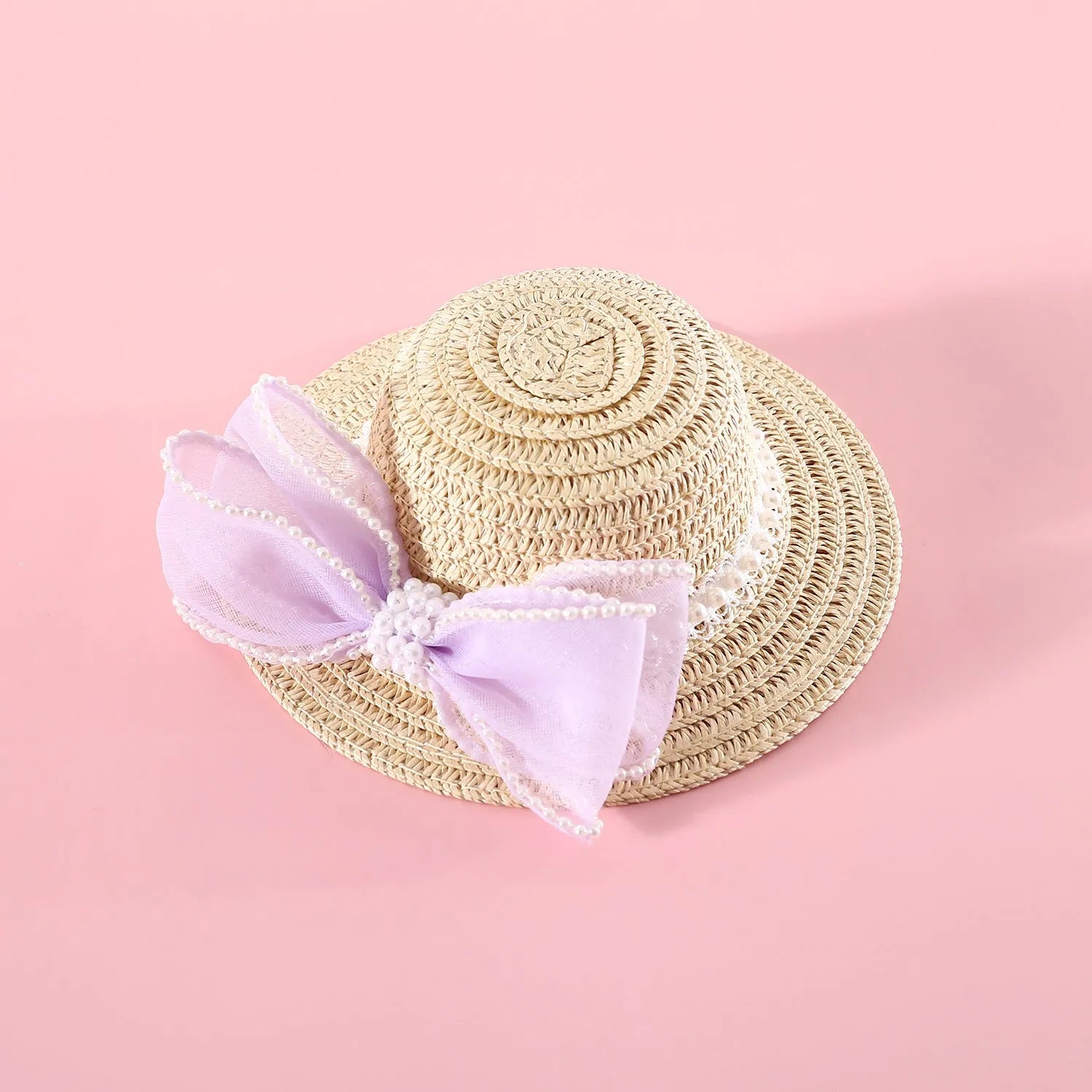 Cat wearing a woven straw hat with a pearl bow decoration in a princess style.
