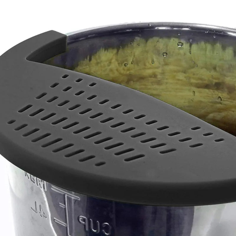 Black silicone food oil drainer snapped onto a pot rim, with liquid being poured off