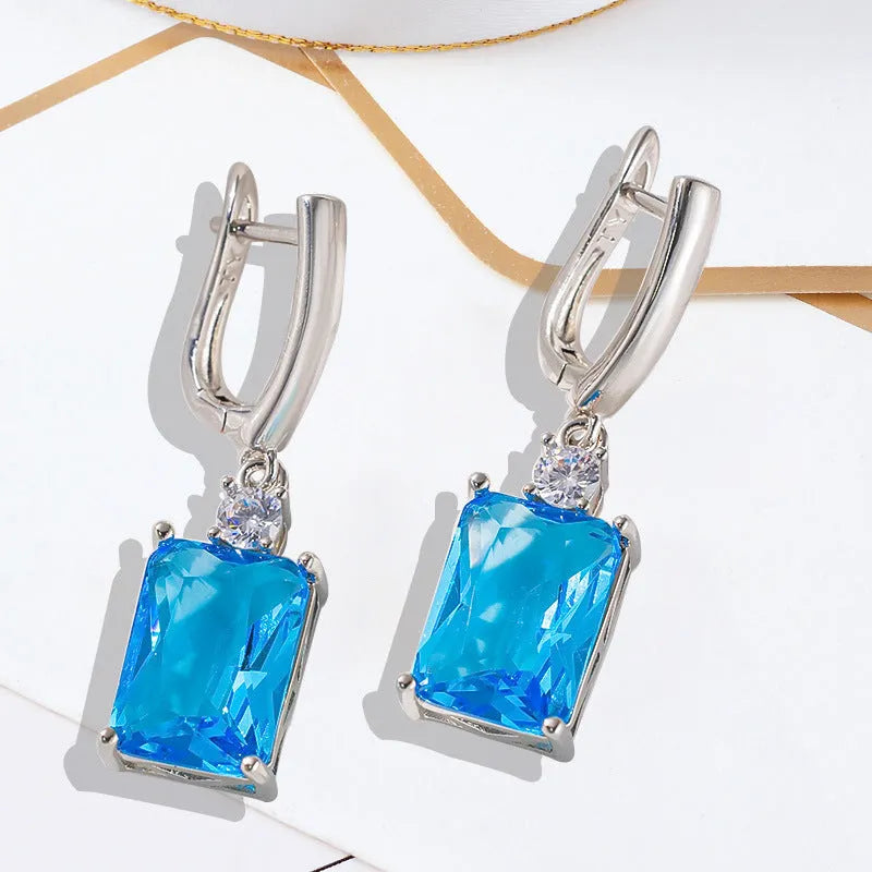 A pair of square-shaped gold-coloured electroplated earrings on a flat surface.
