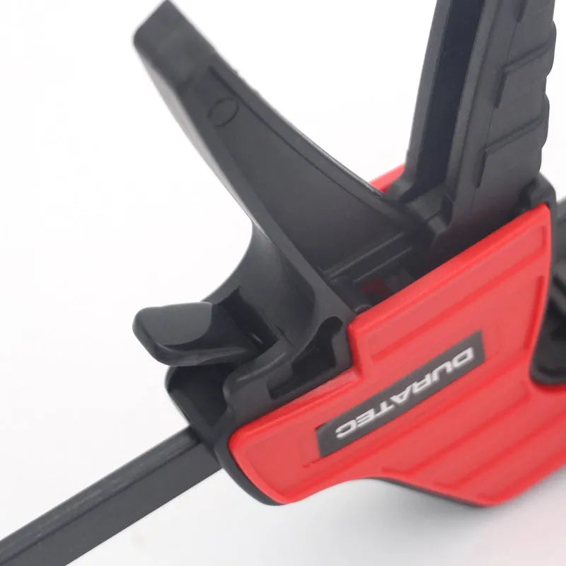Black plastic woodworking clamp with quick-release lever and soft rubber grip pads
