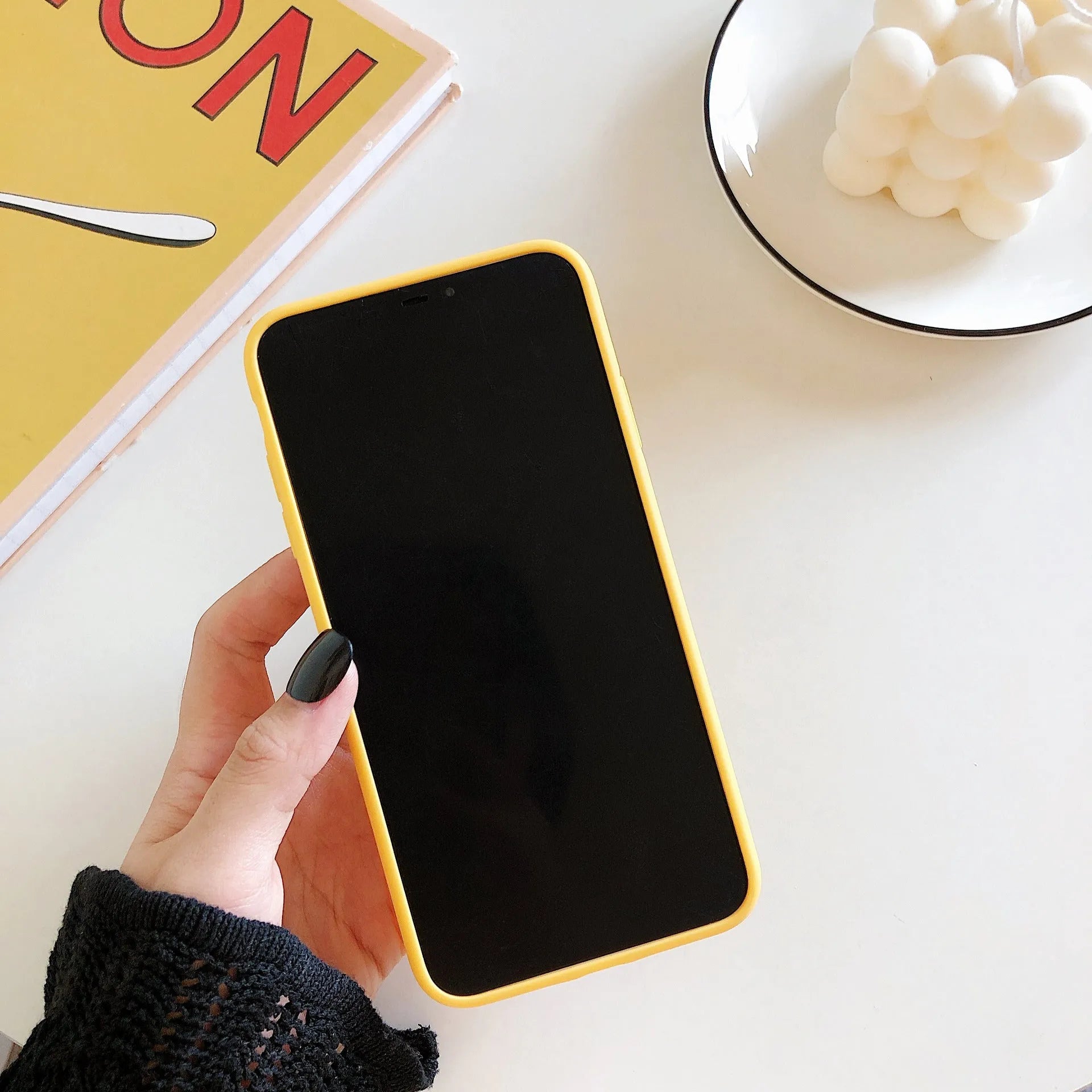 Yellow banana-coloured IMD back cover case for iPhone models 6 through 13 Pro Max on a table.