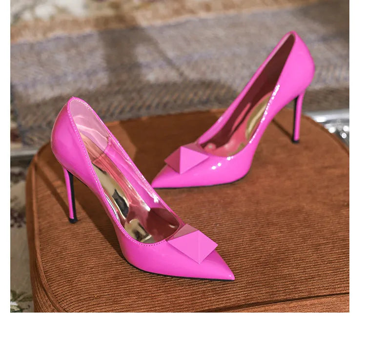 Pink patent leather women's pointed toe stiletto high heels with a buckle detail on the upper.