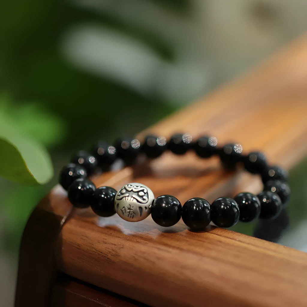 Close-up of a women's bracelet with large 10mm black agate beads and sterling silver details on a wrist.