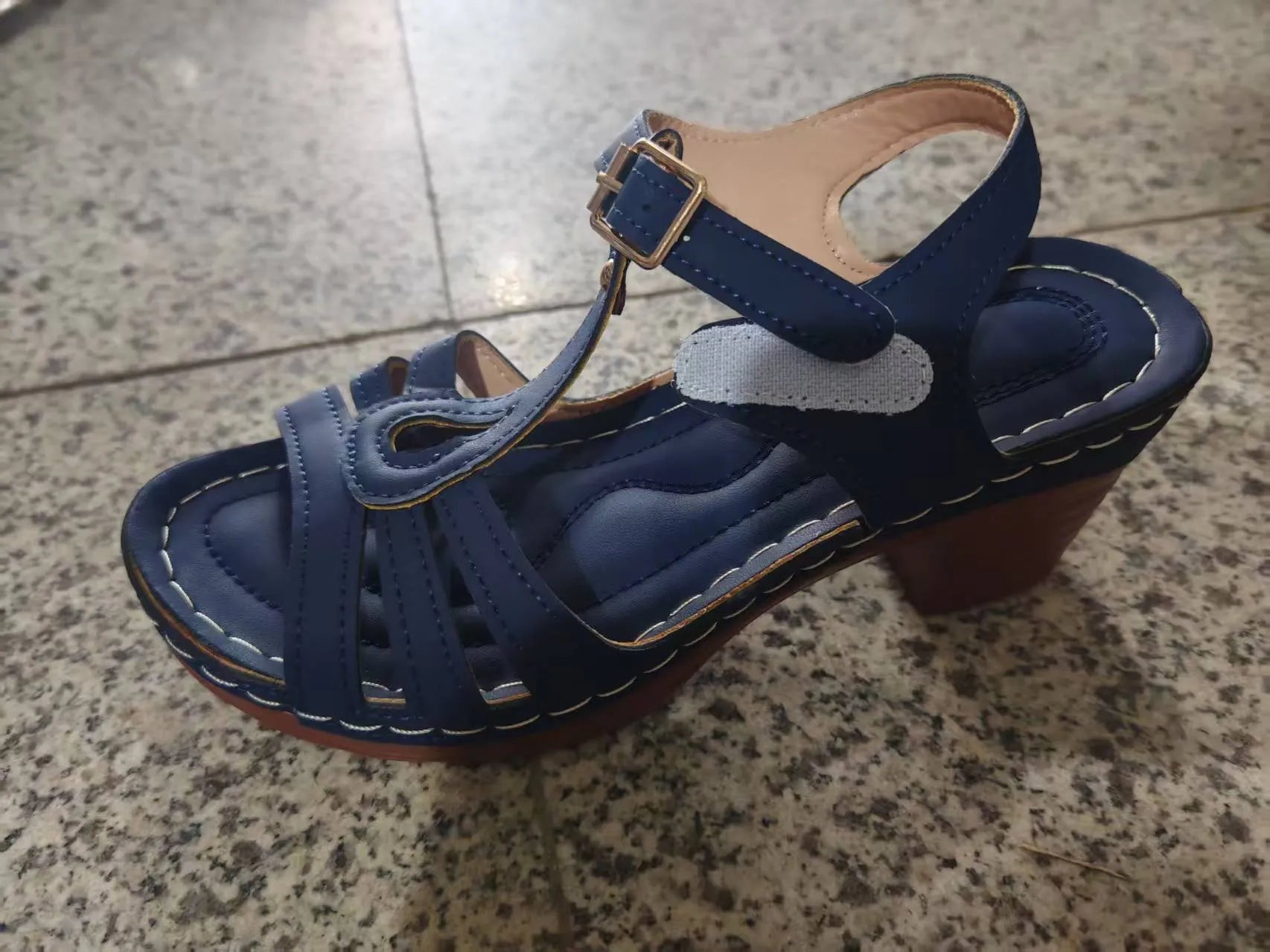 Women's black peep toe wedge platform sandals with a buckle fastening on a wooden surface.